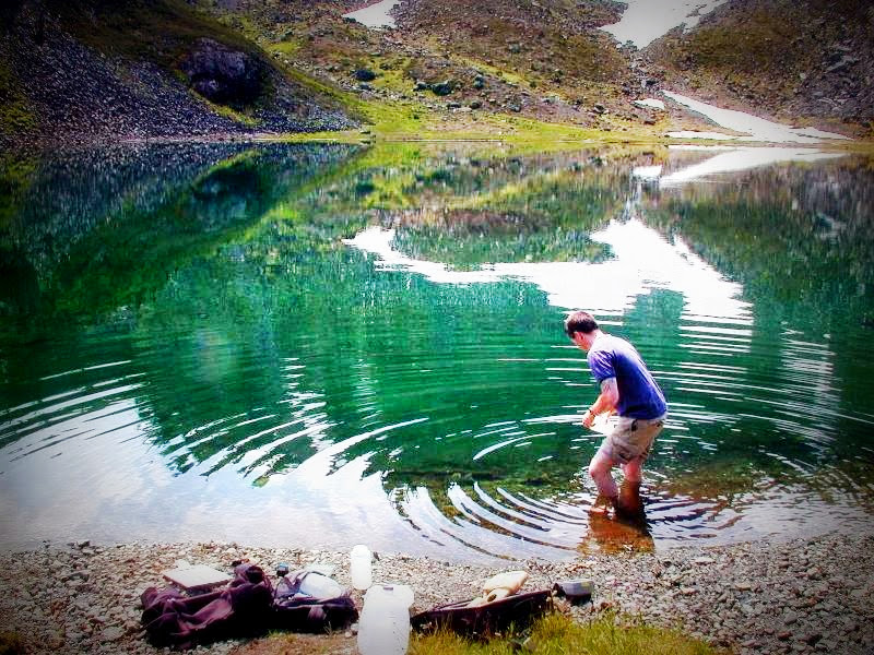 Institute of Watershed Studies intern wading into Upper Bagley Lake to collect a water sample.