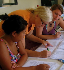 Three students leaning over a map and marking it with a pen