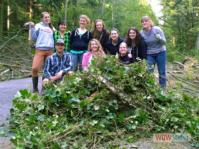Group of Western students standing behind a massive pile of green recently removed invasive plants.