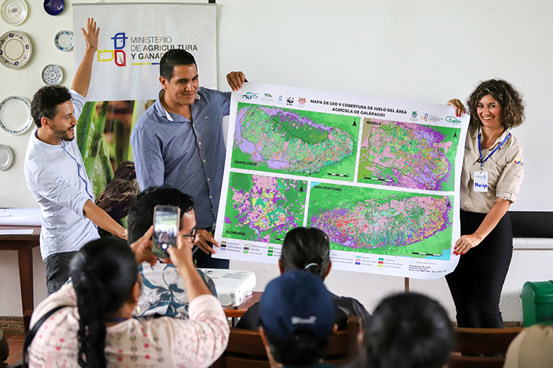 The director of the Ministry of Agriculture (MAG) and the director of the Agency of Biological Control (ABG) are holding up the finished land cover maps at an event in Santa Cruz Island hosted by Conservation International. Photo by ABG