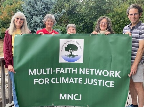 Advocates holding a green banner reading "Multi Faith Network for Climate Justice"