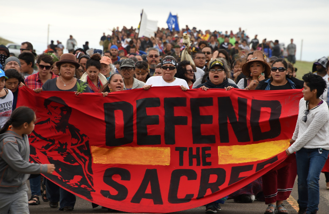 Protesters with a banner reading "defend the sacred". 