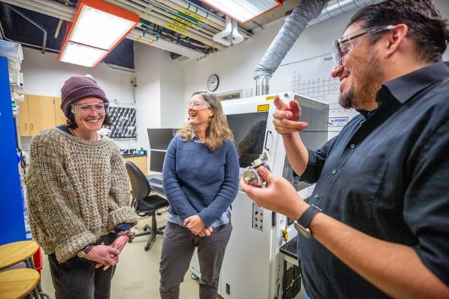 Three people laugh in a laboratory
