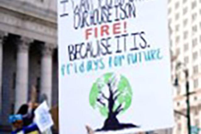 A sign being held up in a rally stating "I want you to act as if our house is on fire - because it is!"