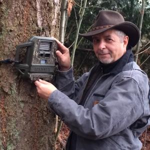 Gregory green investigating a nature cam strapped to a tree