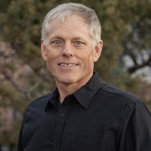 A headshot of Dr. Coblentz in a black collared shirt outside