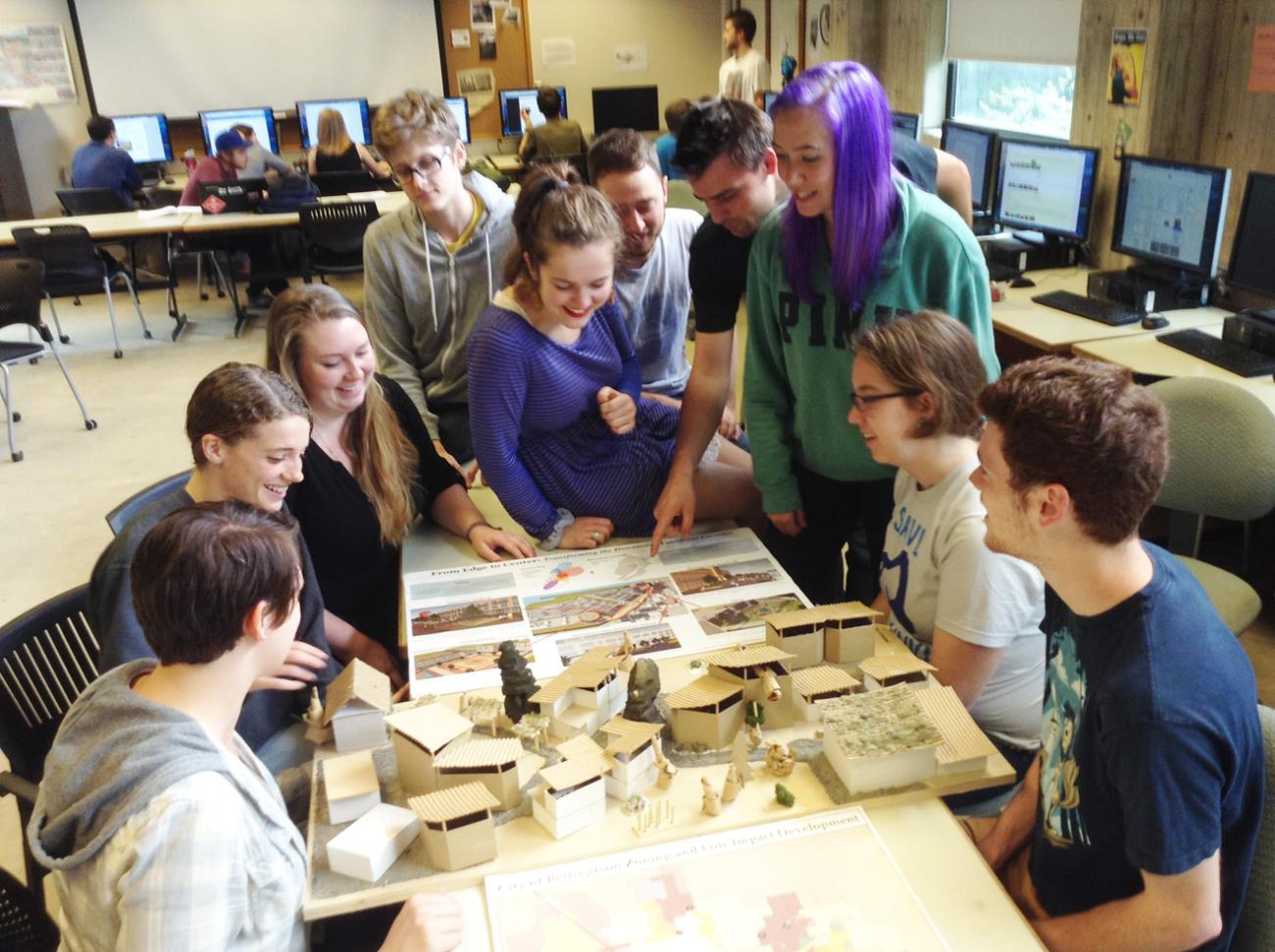 Students around a table looking at designs