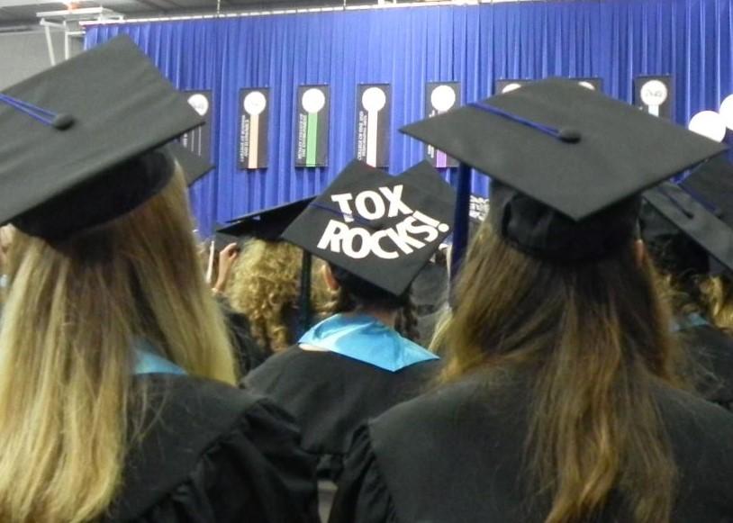 Students in cap and gown, one cap says "ToxRocks" on it.