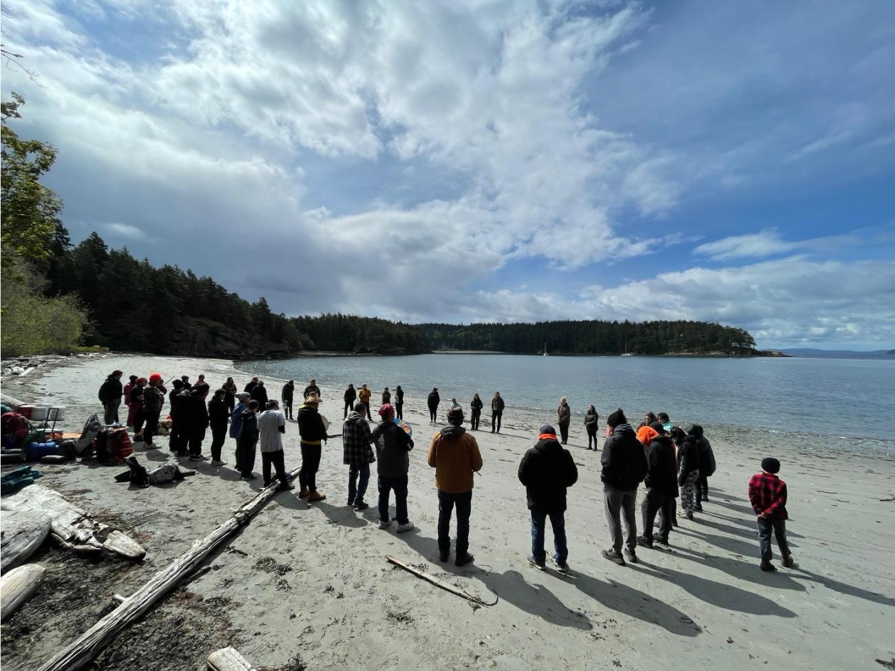 Participants in Spring Block stand in a circle on a beach