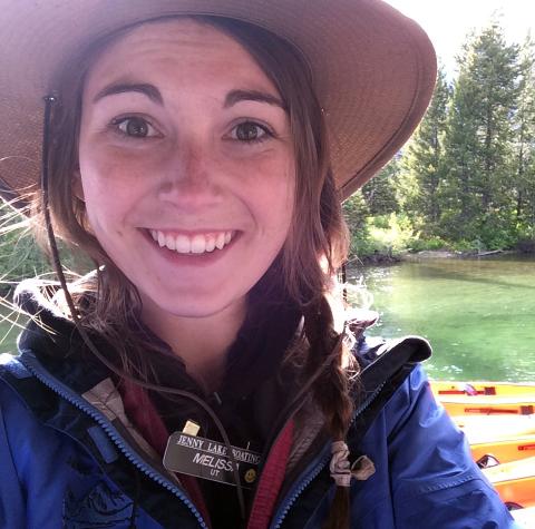 Portrait of Melissa Ruth smiling enthusiastically, wearing a tan safari hat and a blue jacket