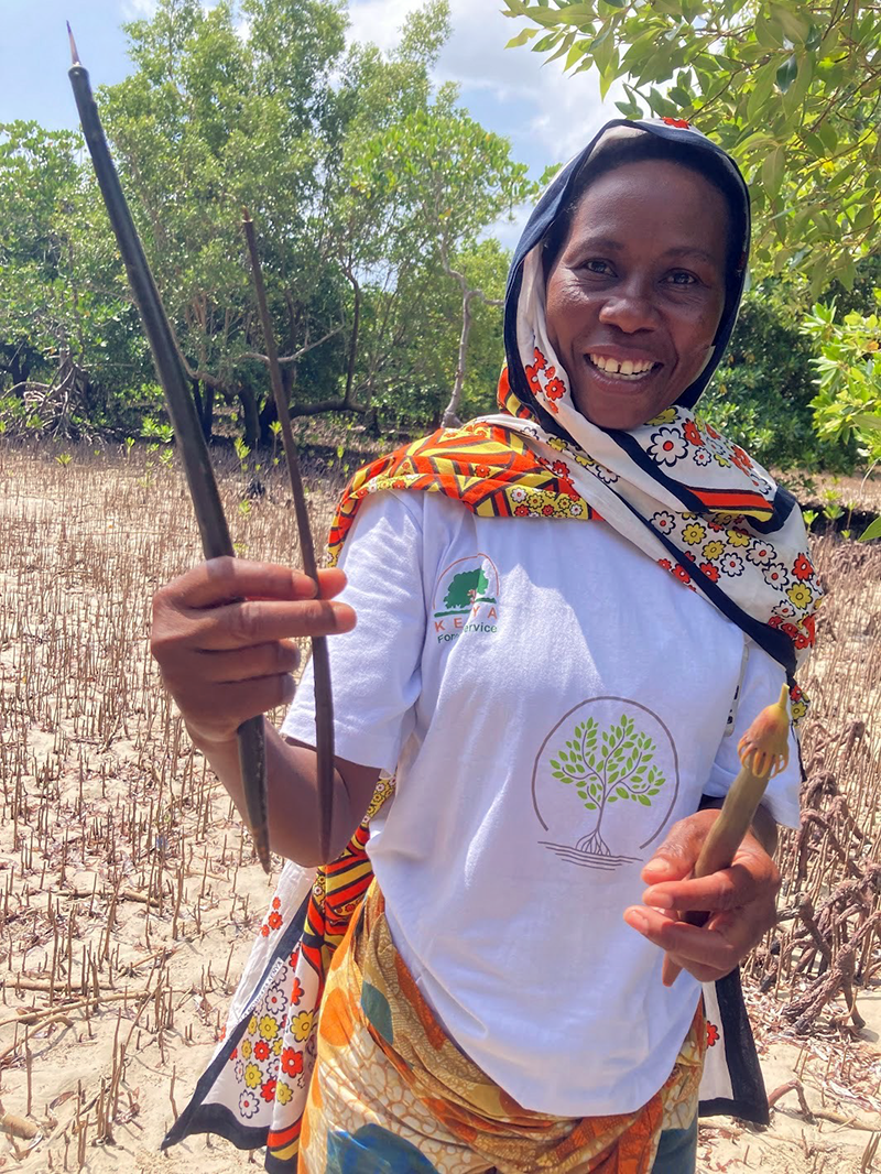 A member of the Tunusuru Conservation Women Group holds up a mangrove seedling.