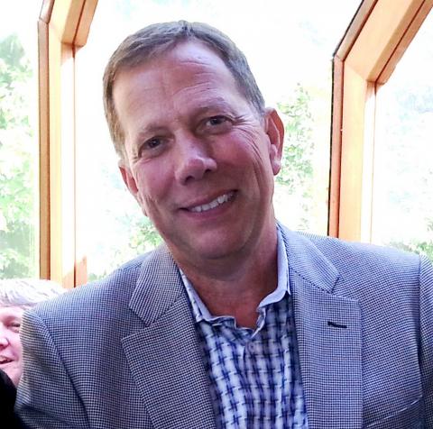 Portrait of Ken Johnson smiling at the camera wearing a grey suit